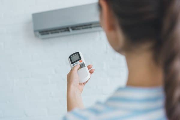 selective focus of woman turning on air conditioner with remote control